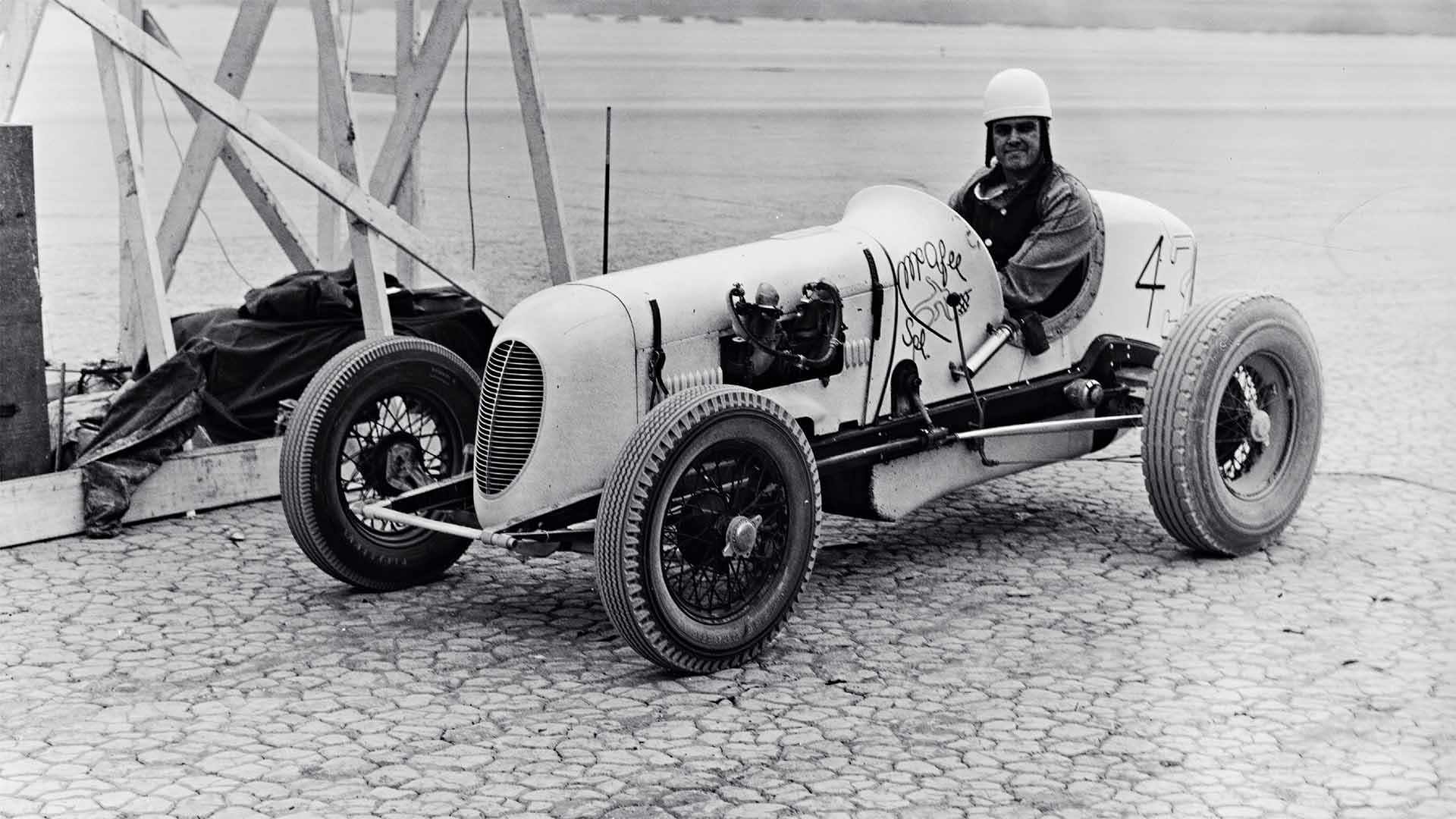 Vintage racing car with driver in a garage setting