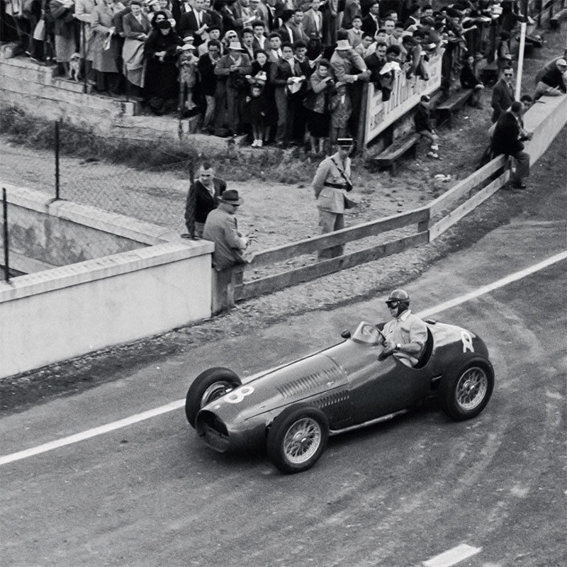 Vintage race car on a track with spectators in the background