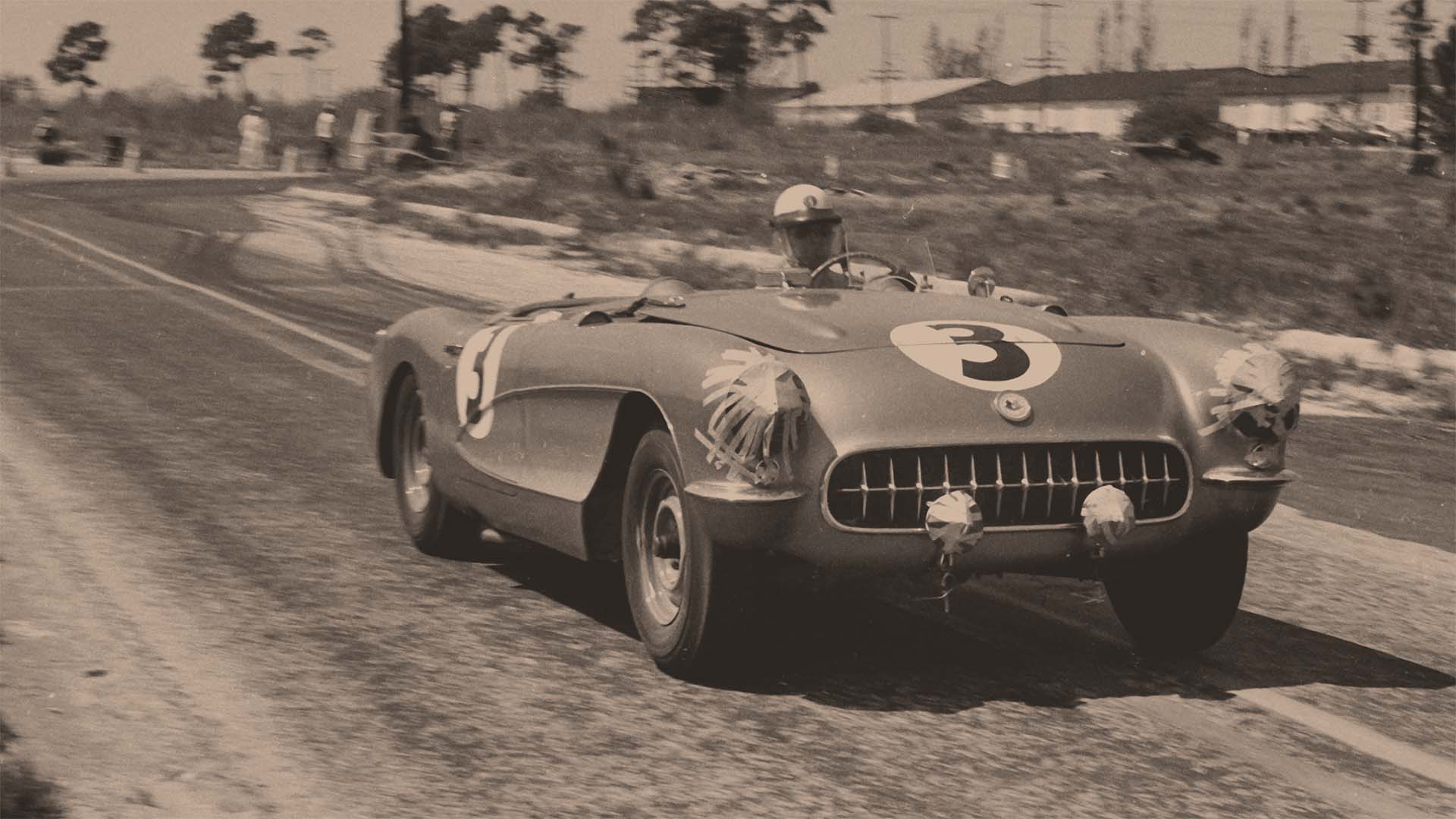 Vintage race car with number 3 on a track, black and white photo