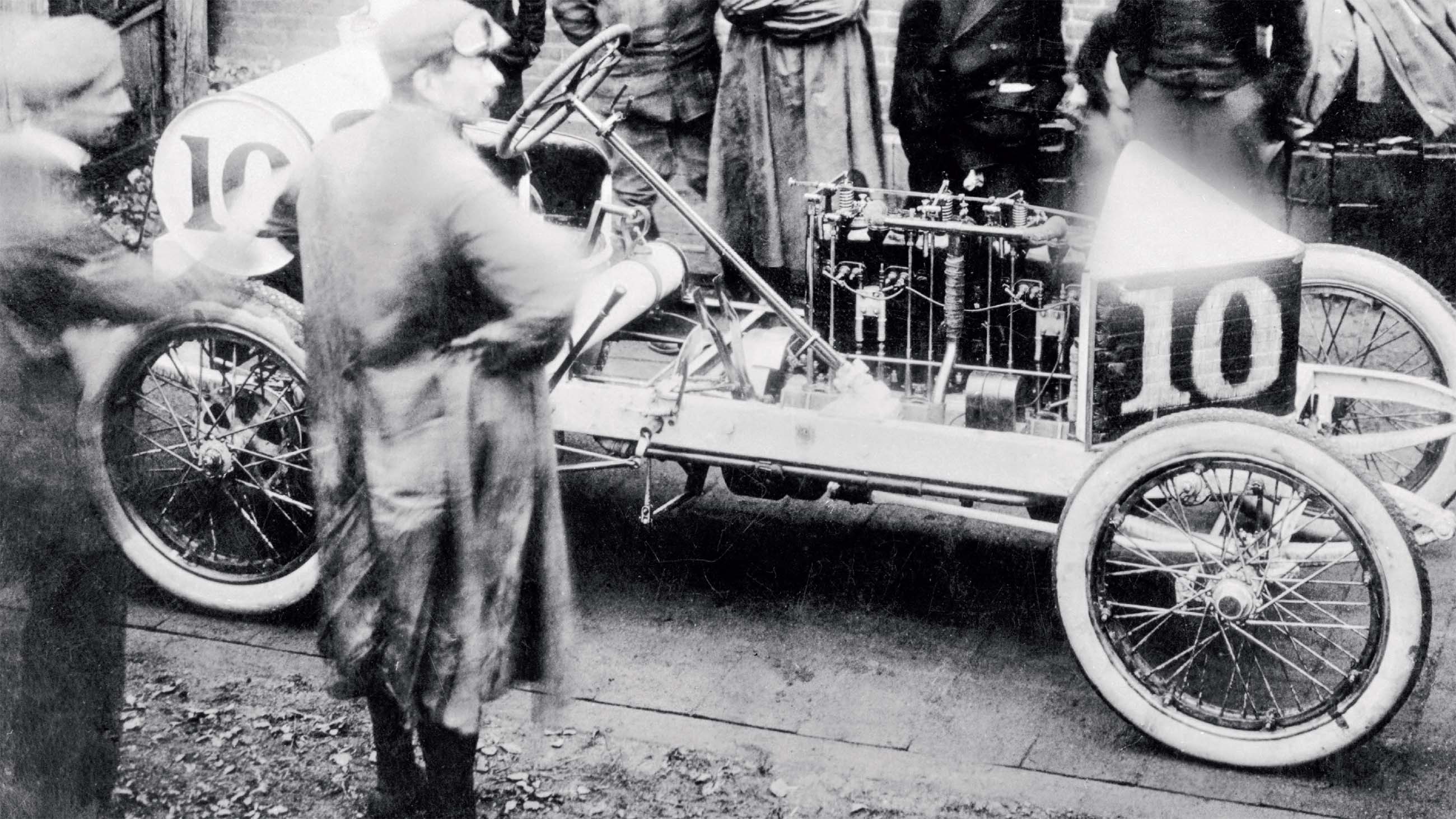 Vintage black and white photograph of early automobiles and people around them