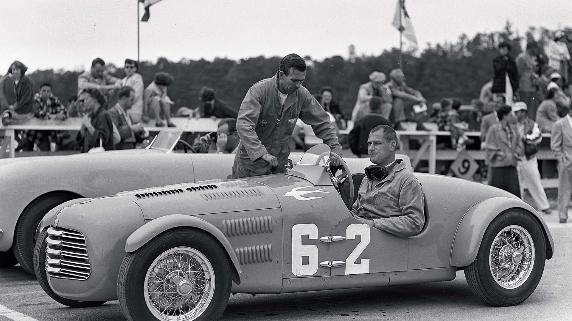 Vintage race car with driver and co-driver in a black and white photo